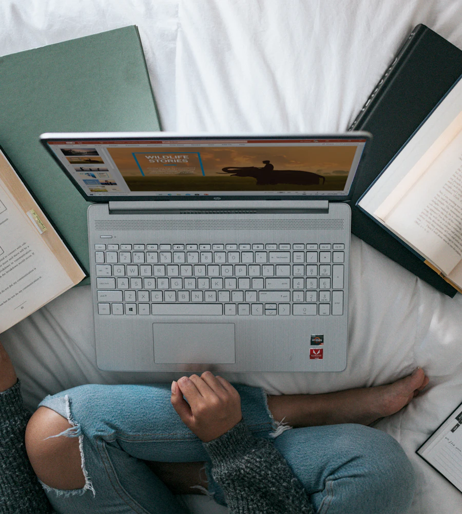 Estudante com notebook e livros abertos, estudando em casa