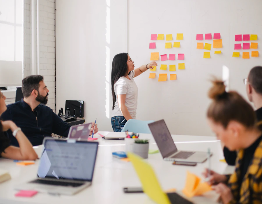 Jovem apresentando um planejamento com post-its para a equipe